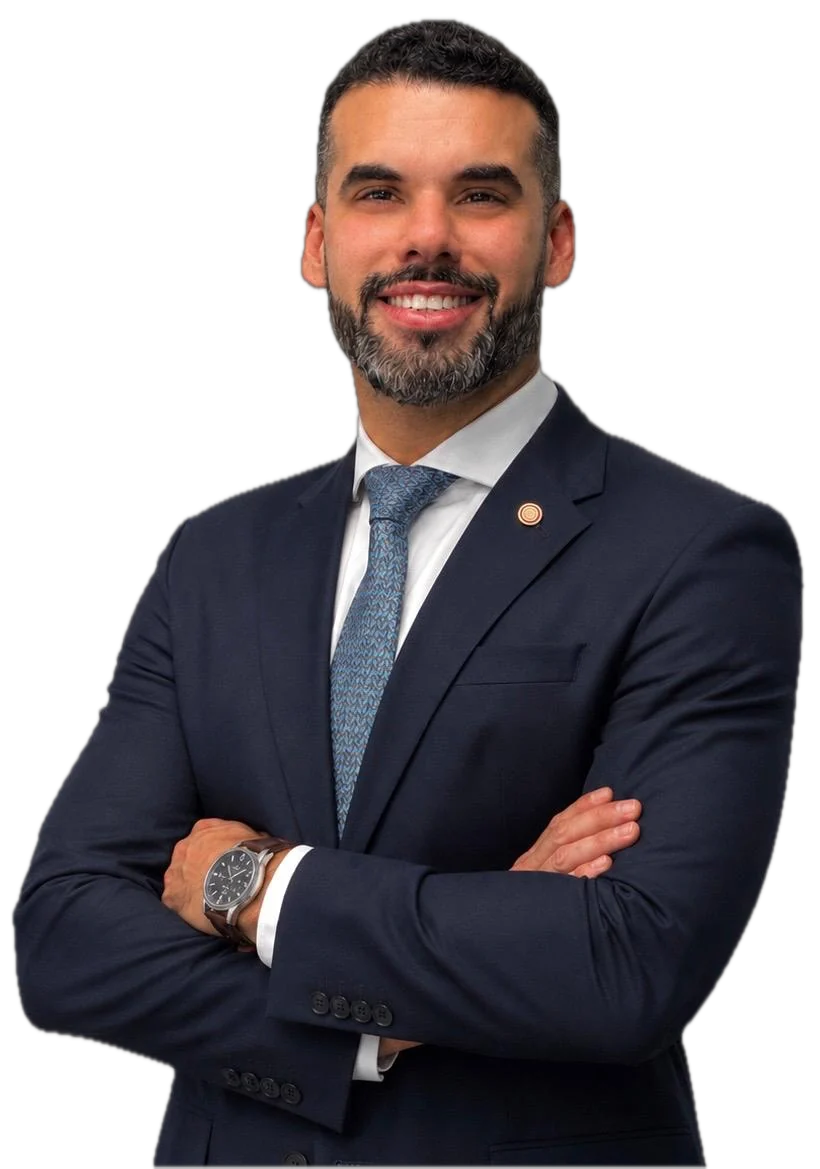 Guilherme Bittencourt, de terno azul-marinho, sorrindo, com os braços cruzados